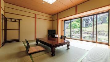 Een traditionele Japanse kamer met tatami vloerbedekking, een houten tafel en een schuifdeur naar een tuin.