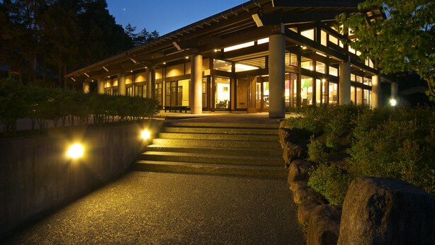 A modern building with a covered entrance, large windows, and steps leading up to the door. - Hotel Kikori (Hida)
