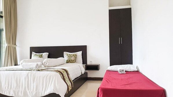 Un dormitorio con cama, mesita de noche, armario y ventana con cortinas.