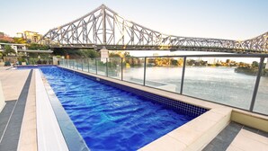 A swimming pool with a view of a bridge and buildings in the background.