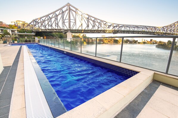 A swimming pool with a view of a bridge and buildings in the background. - River Place hosted by AAB (Brisbane)