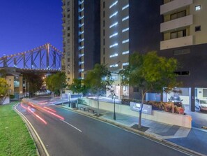 A modern hotel with a glass facade, a pedestrian walkway, and a parking area. - River Place hosted by AAB (Brisbane)
