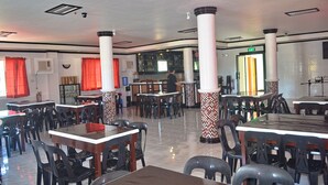 Un restaurant doté de nombreuses tables et chaises, d’un bar et d’un panneau de sortie bien visible.