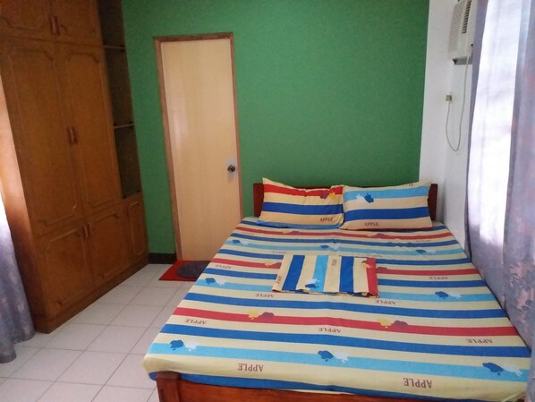 Une chambre à coucher avec un lit, des murs verts, une armoire en bois et une porte.