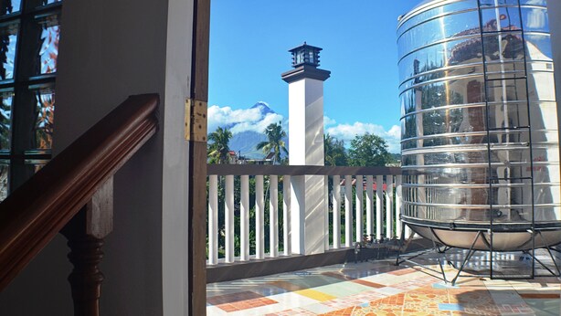 Un balcon offrant une vue sur une montagne, un phare et une structure moderne en verre.