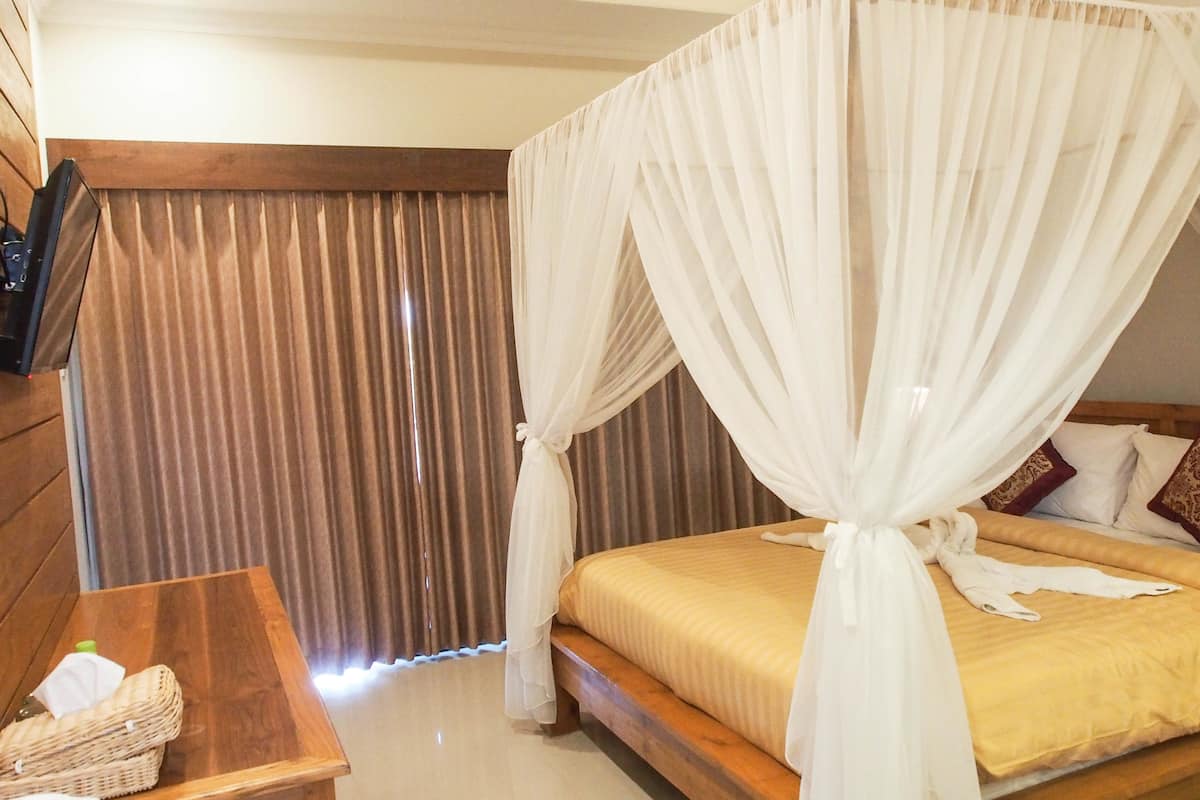 A bedroom with a wooden bed, white canopy, brown curtains, and a wooden nightstand with a tissue box.