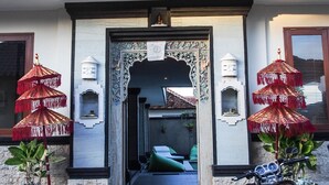 A building entrance with a decorative archway, a balcony with railings, and a motorcycle parked outside. - Lebak Bali Nelayan (Canggu)