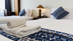 Une chambre d’hôtel avec deux lits, une lampe, un téléphone et une serviette soigneusement pliée posée sur l’un des lits.