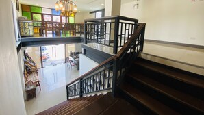 Un intérieur à plusieurs niveaux, avec un escalier, un lustre et une vue sur l’extérieur.