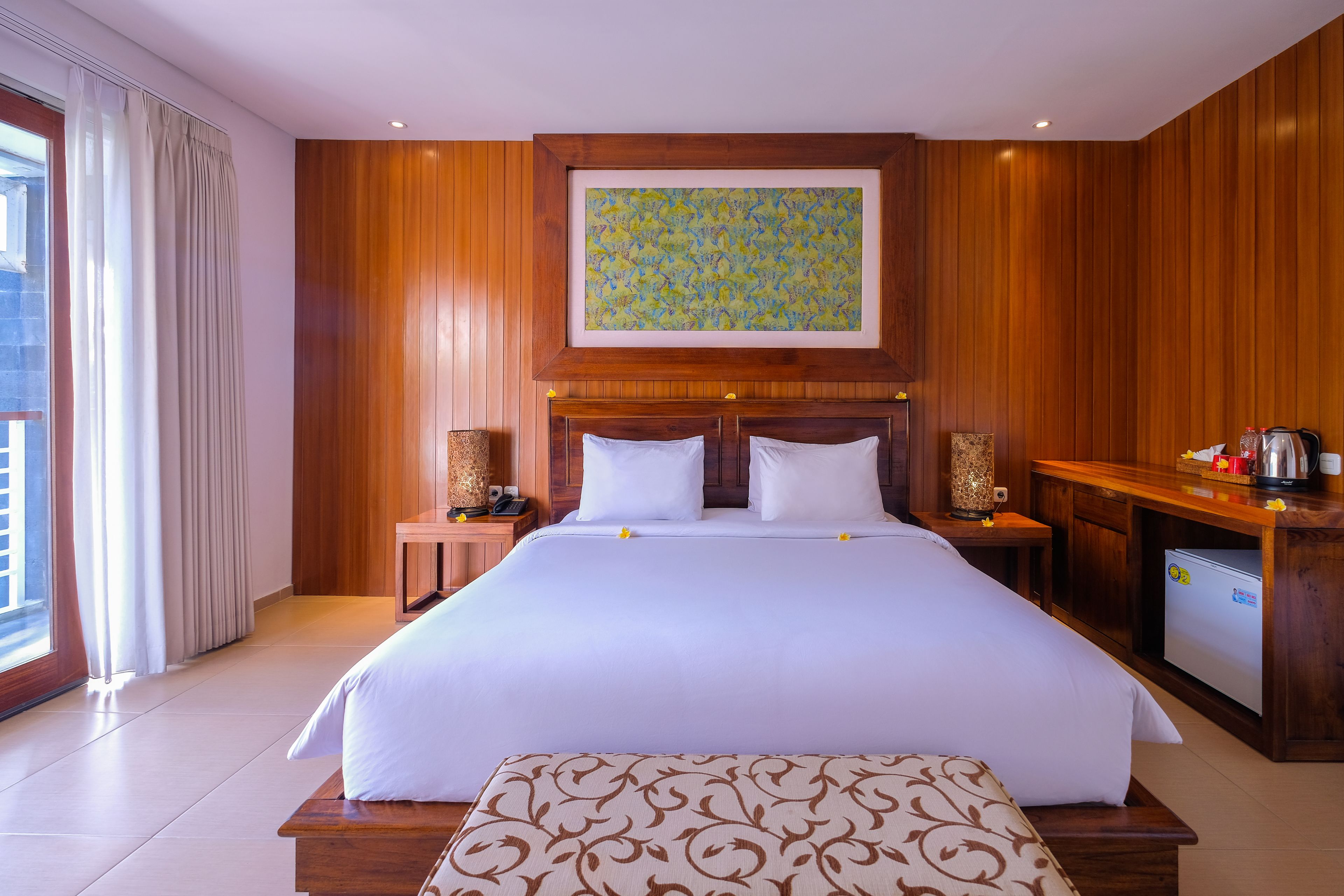 A large bed with white linens, a wooden headboard, and a small bedside table with a lamp.