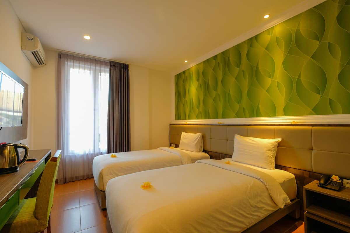 A hotel room with two beds, a desk, a chair, a coffee maker, and a telephone.
