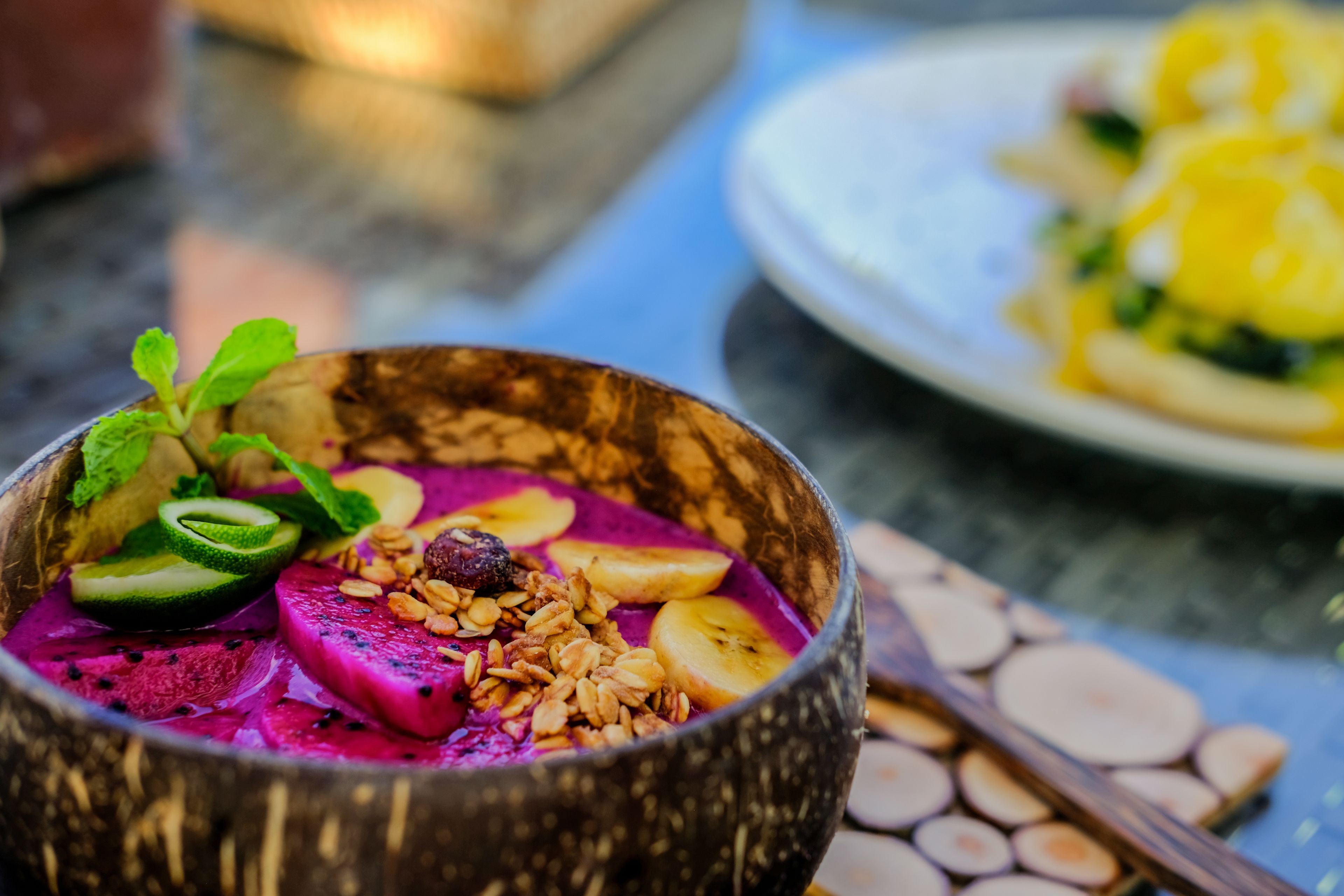 A bowl of colorful smoothie with fruits and granola.