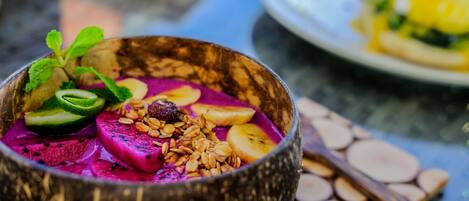 A bowl of colorful smoothie with fruits and granola.