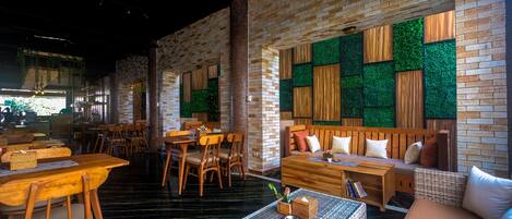 A restaurant with brick walls, wooden furniture, and green wall accents.