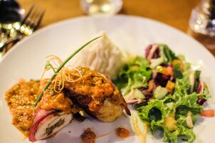 Prato com salada e carne acompanhada de molho.