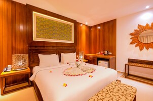 Ein Hotelzimmer mit einem großen Bett, Holzwandverkleidung, einem spiegelnden Sonnensymbol und einem gerahmten Kunstwerk über dem Bett.