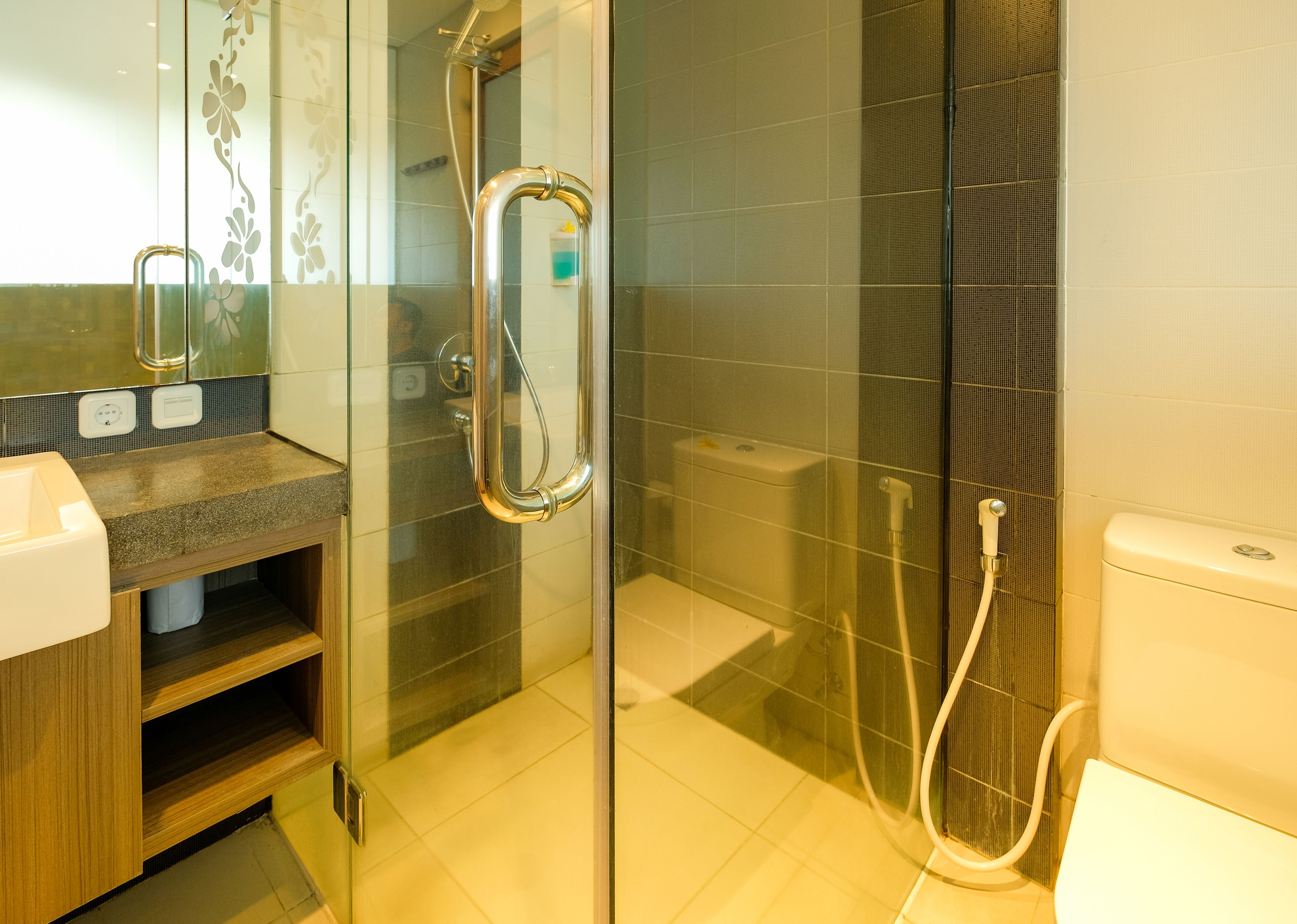 A modern bathroom with a glass-enclosed shower, a toilet, and a vanity with a mirror.