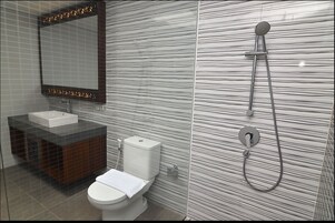 Un baño moderno con ducha de vidrio, inodoro blanco y tocador con lavamanos.