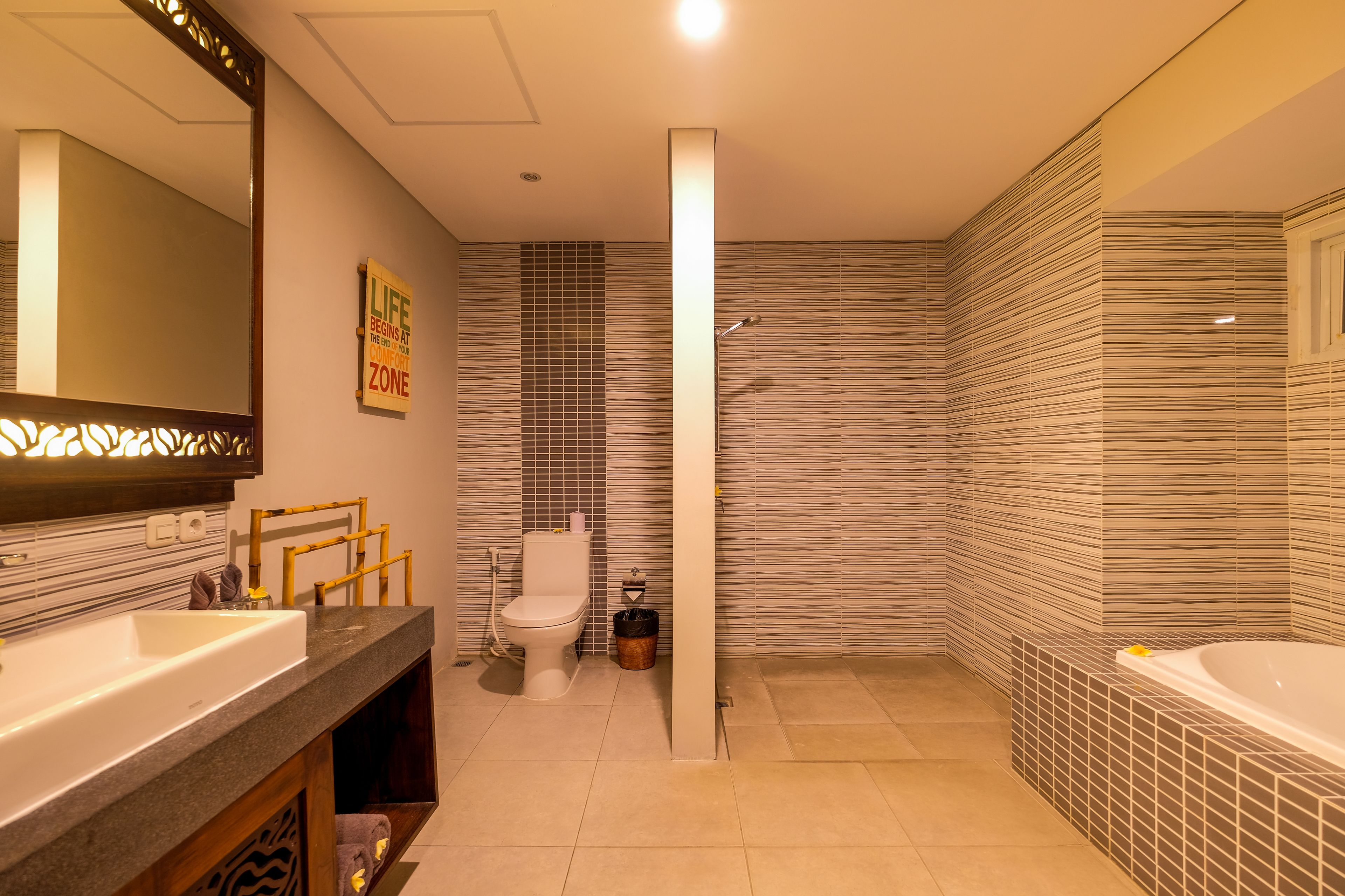 Un baño moderno con una bañera grande, un inodoro separado y un tocador con espejo.