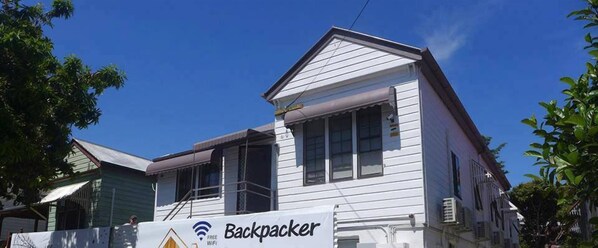 A white two-story house with a sign that reads "Backpacker" and "Free WiFi". - Gonow Family Backpackers Hostel (West End)