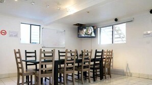A conference room with a long table and chairs, a whiteboard, and a TV screen. - Gonow Family Backpackers Hostel (West End)