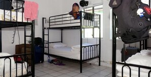 A dormitory room with bunk beds, a suitcase, and a bed with a pink towel. - Gonow Family Backpackers Hostel (West End)