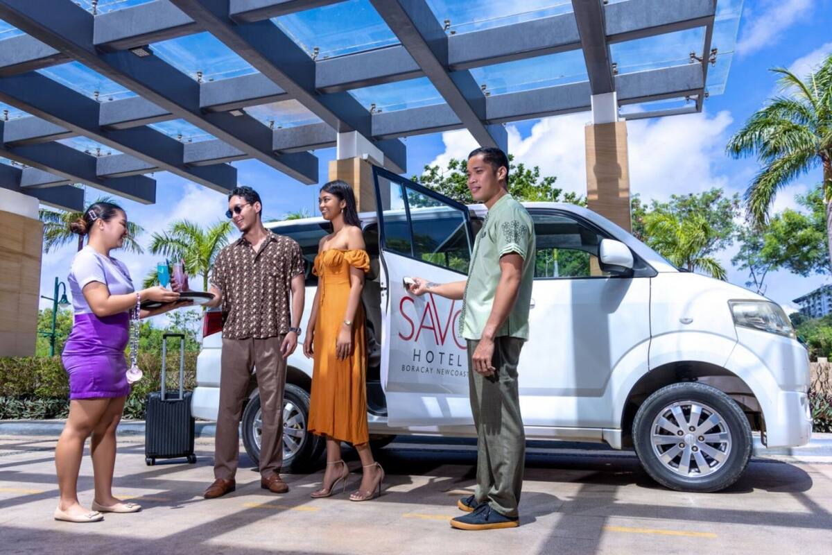 A group of people standing in front of a white van with 'SAVC HOTEL BORACAY NEWCOAST' written on it.
