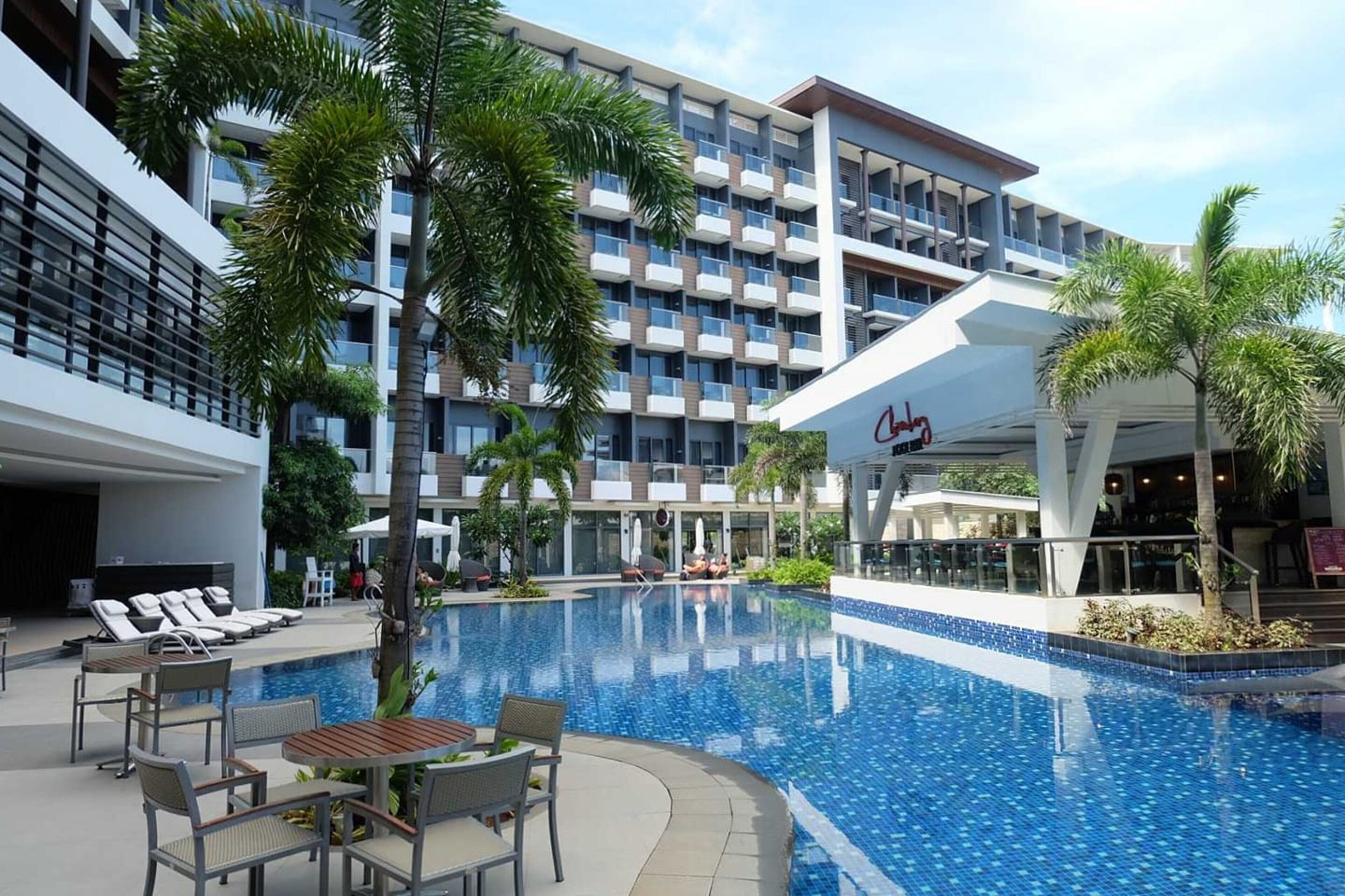 Un hotel con piscina, sillas de descanso y restaurante.