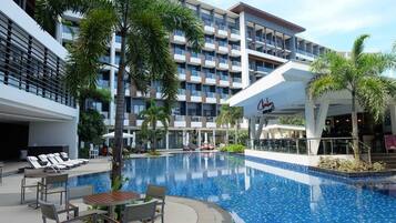 Un hotel con piscina, sillas de descanso y restaurante.