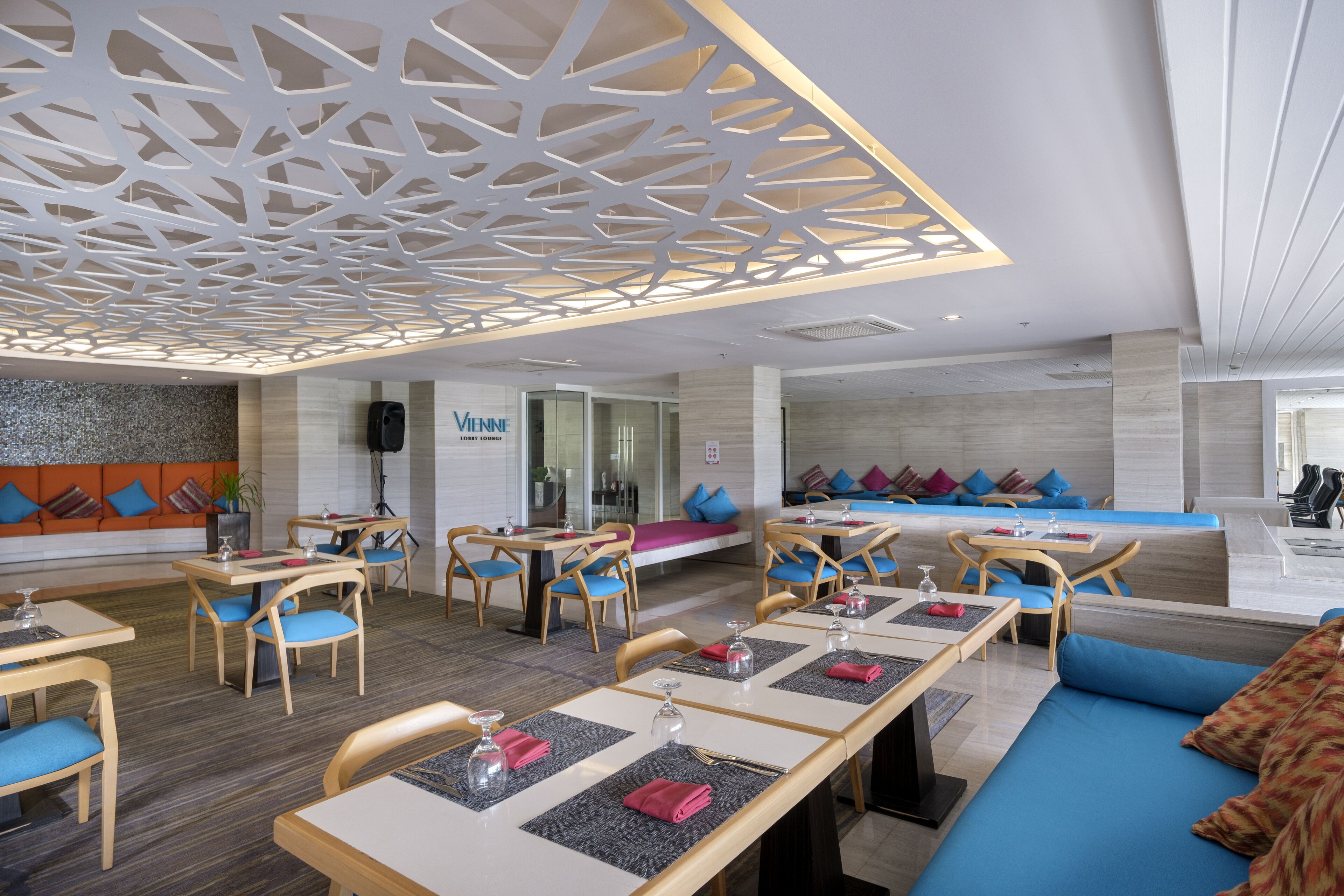 Een moderne hotellobby met zithoeken, een receptiebalie en een zichtbaar bord met daarop 'Vienna Lobby'.