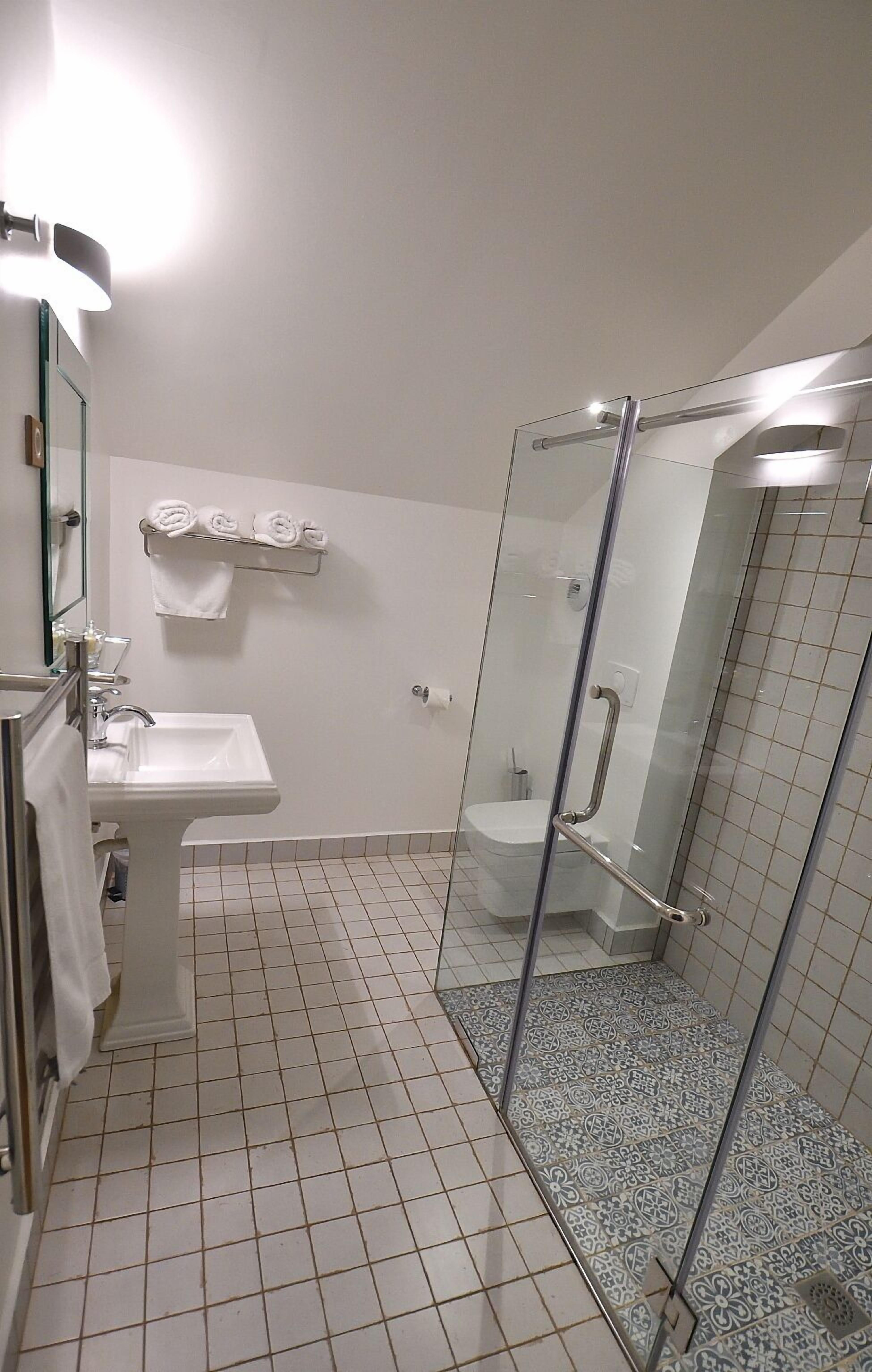 Une salle de bain avec une douche à parois de verre, un lavabo et des toilettes.