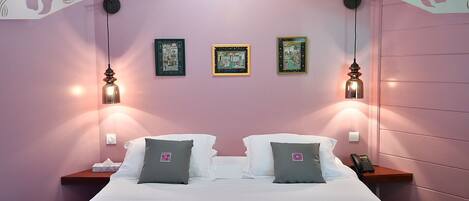 Ein Hotelzimmer mit einem Bett, zwei Nachttischen und drei gerahmten Bildern an der Wand.