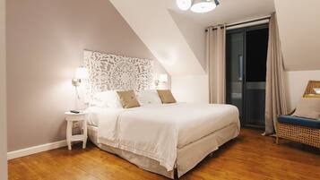 A bedroom with a bed, bedside tables, a decorative headboard, a wicker chair, and a sliding glass door.