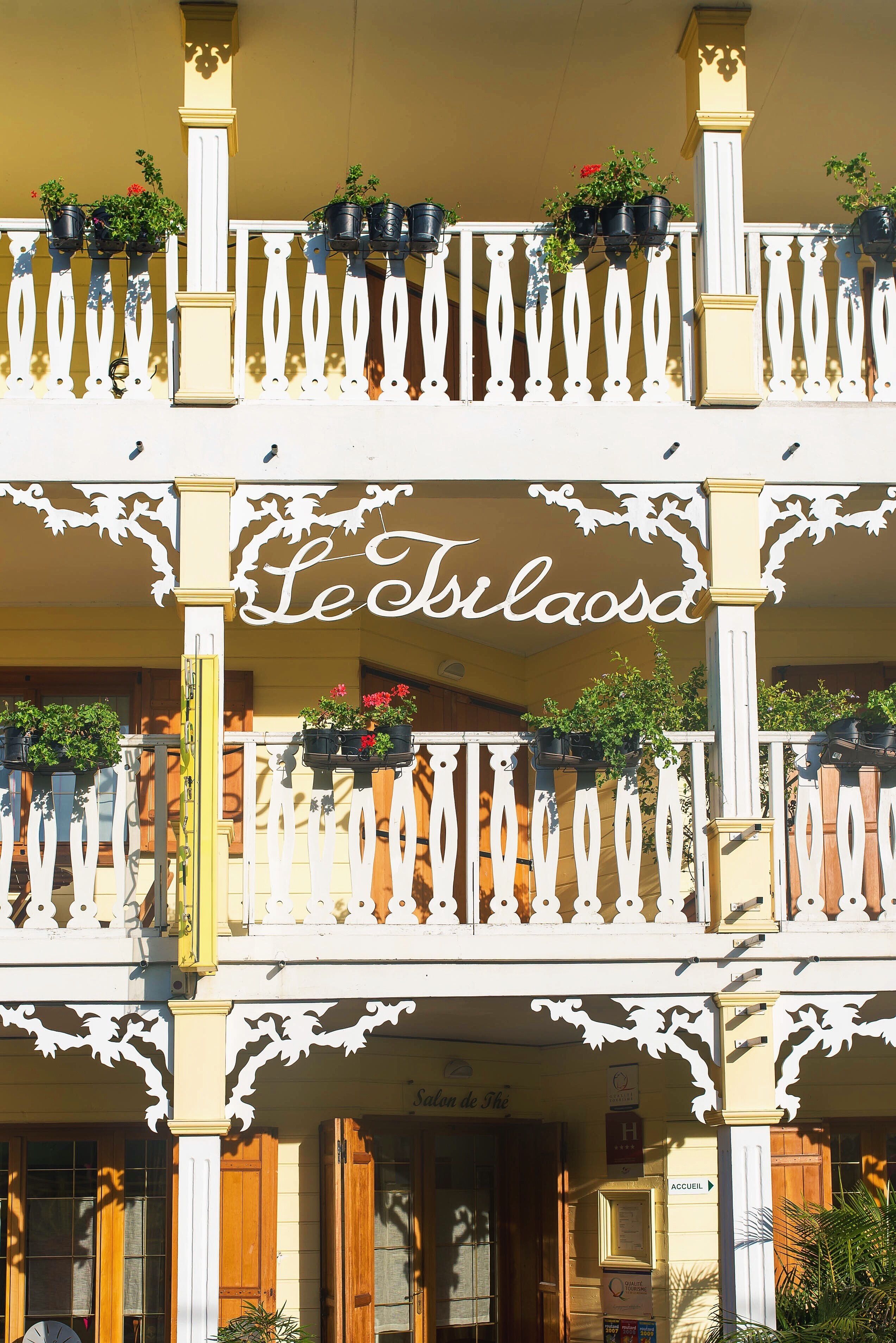 A hotel facade with a balcony adorned with potted plants and a sign reading "Leilaosa."