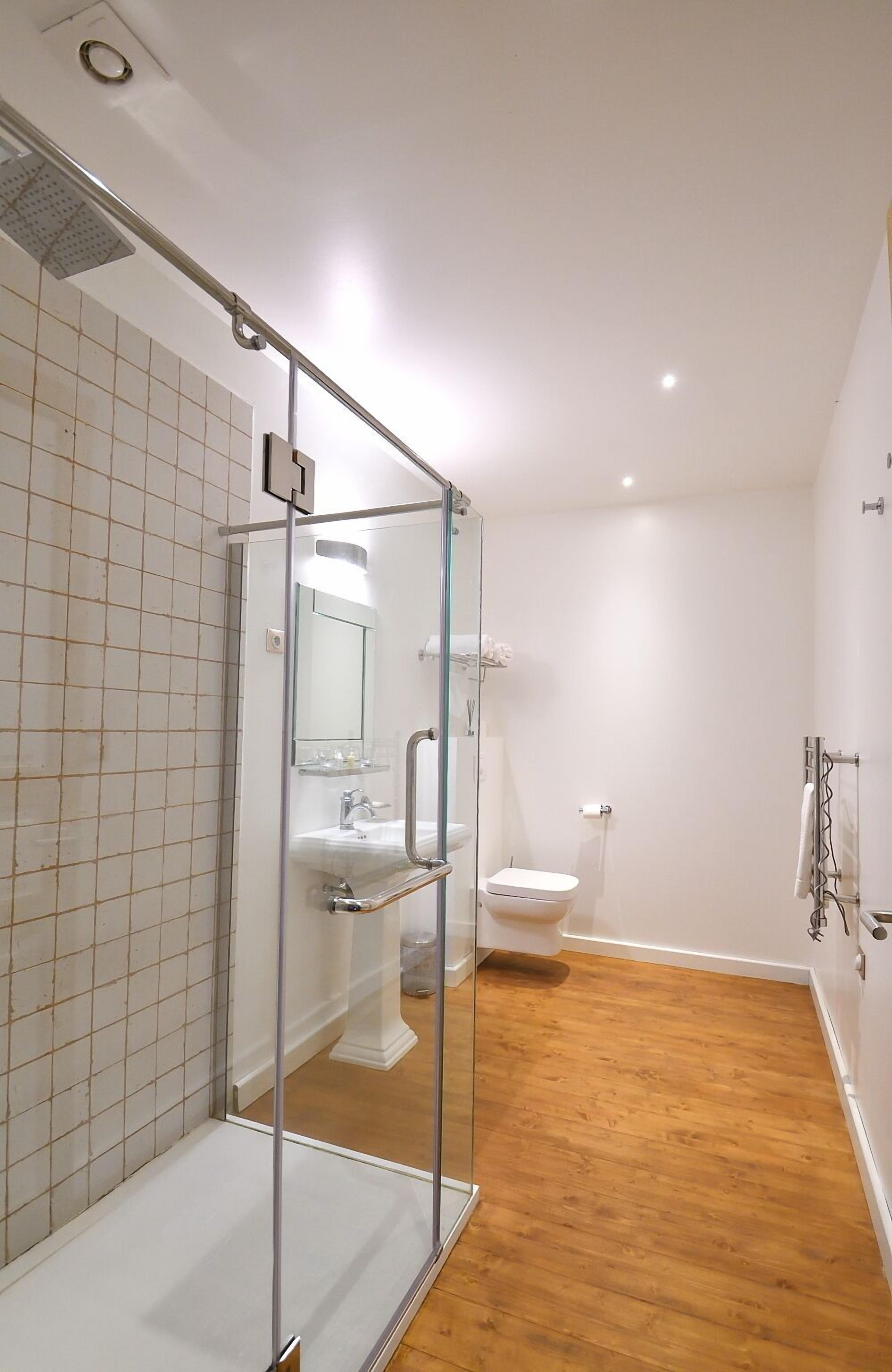 A modern bathroom with a glass shower enclosure, a white sink, and a toilet.