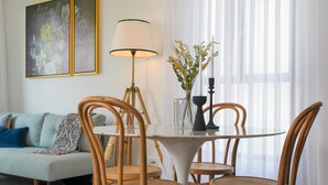 A dining area with a round table, four wooden chairs, a floor lamp, and a vase with flowers. - Mr. Brooklyn - By TLV2GO (Tel Aviv)
