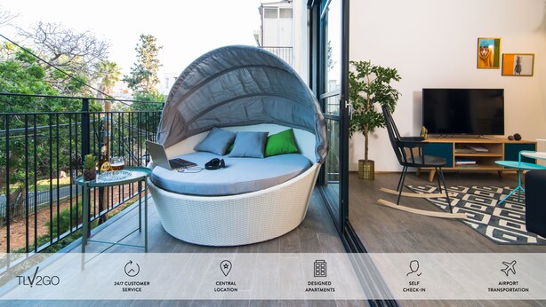 A modern living room with a curved seating area, a flat-screen TV, and a view of the outdoors. - Mr. Brooklyn - By TLV2GO (Tel Aviv)