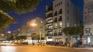 A multi-story building with balconies, a tree-lined street, and parked vehicles. - Mr. Brooklyn - By TLV2GO (Tel Aviv)