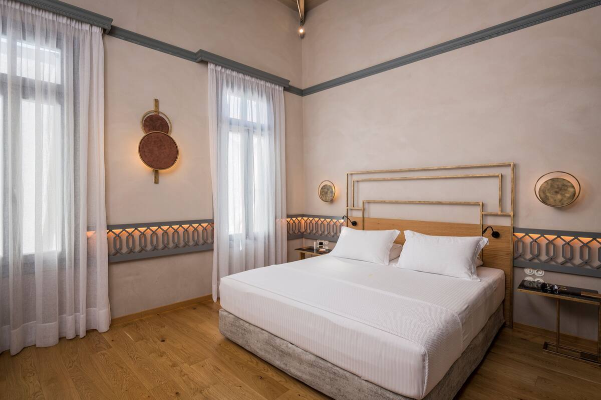 A neatly arranged bedroom with a large bed, two bedside tables, and a headboard with a geometric pattern.