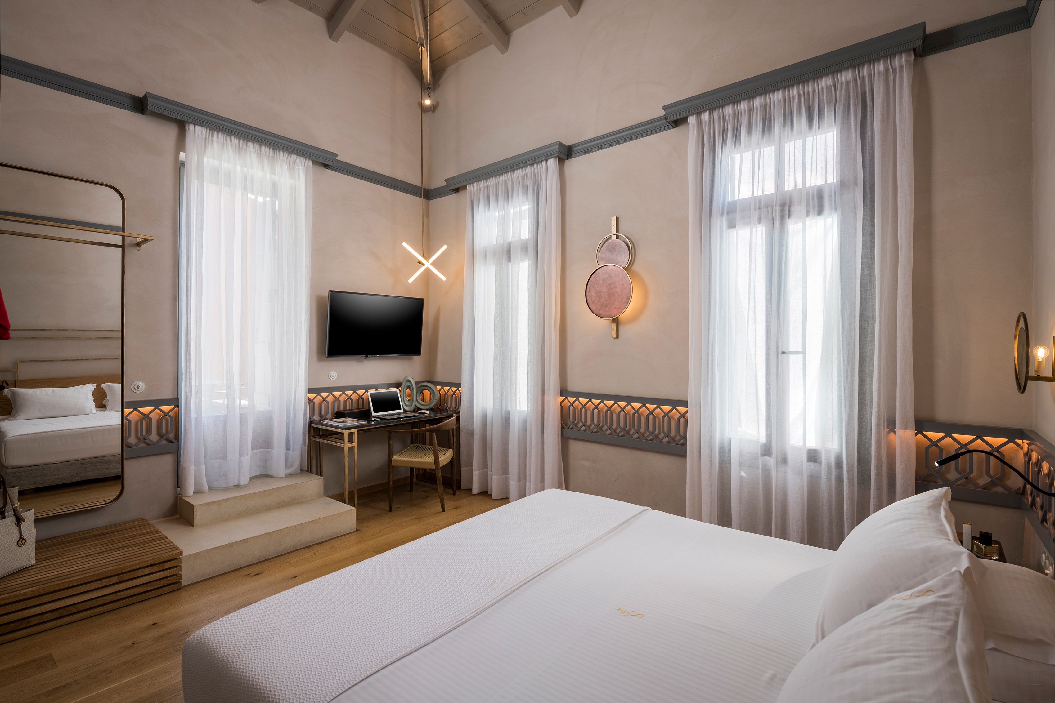 A hotel room with a large bed, a desk with a laptop, a TV, and a bunk bed.