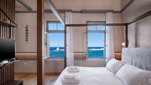 Une chambre avec un grand lit, une télévision et une vue sur la mer.