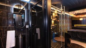 Un baño moderno con un espejo grande, paredes de mármol negro y una bañera negra.