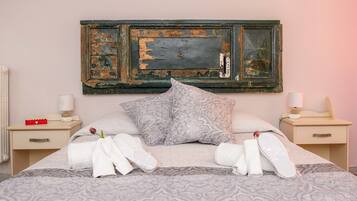 Una cama bien tendida con ropa de cama estampada, dos mesitas de noche con lámparas y una decoración rústica en la pared.