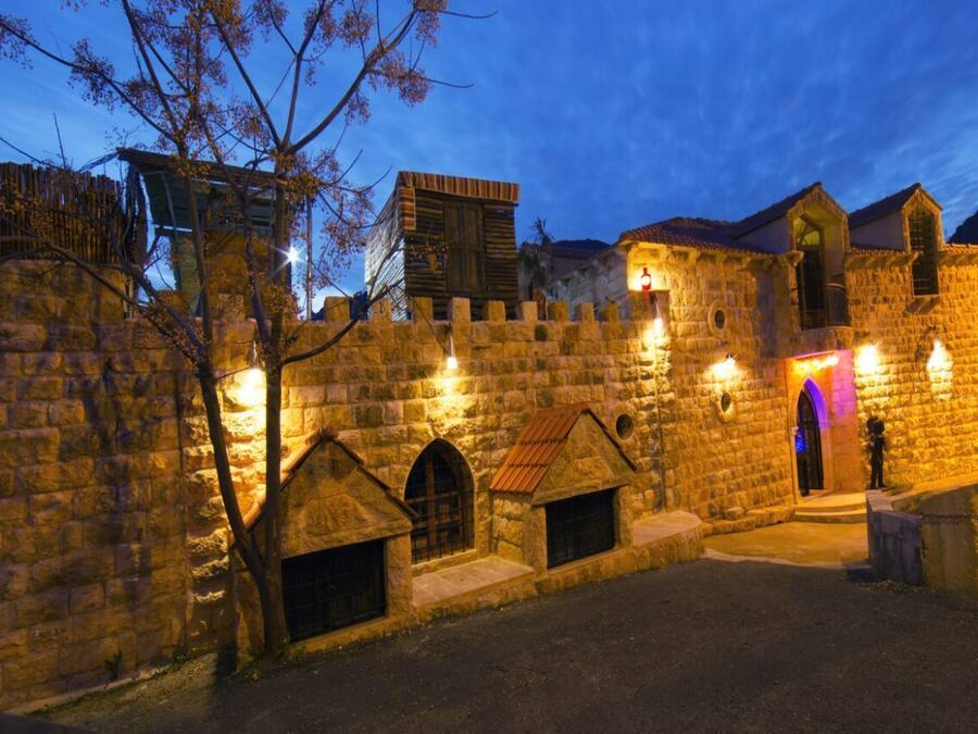 A historic stone building with arched windows and a central doorway, illuminated by warm lighting.