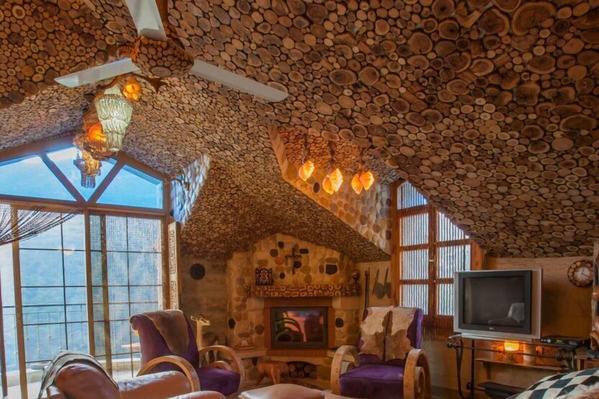 A cozy living room with a stone ceiling, leather sofas, and a fireplace.