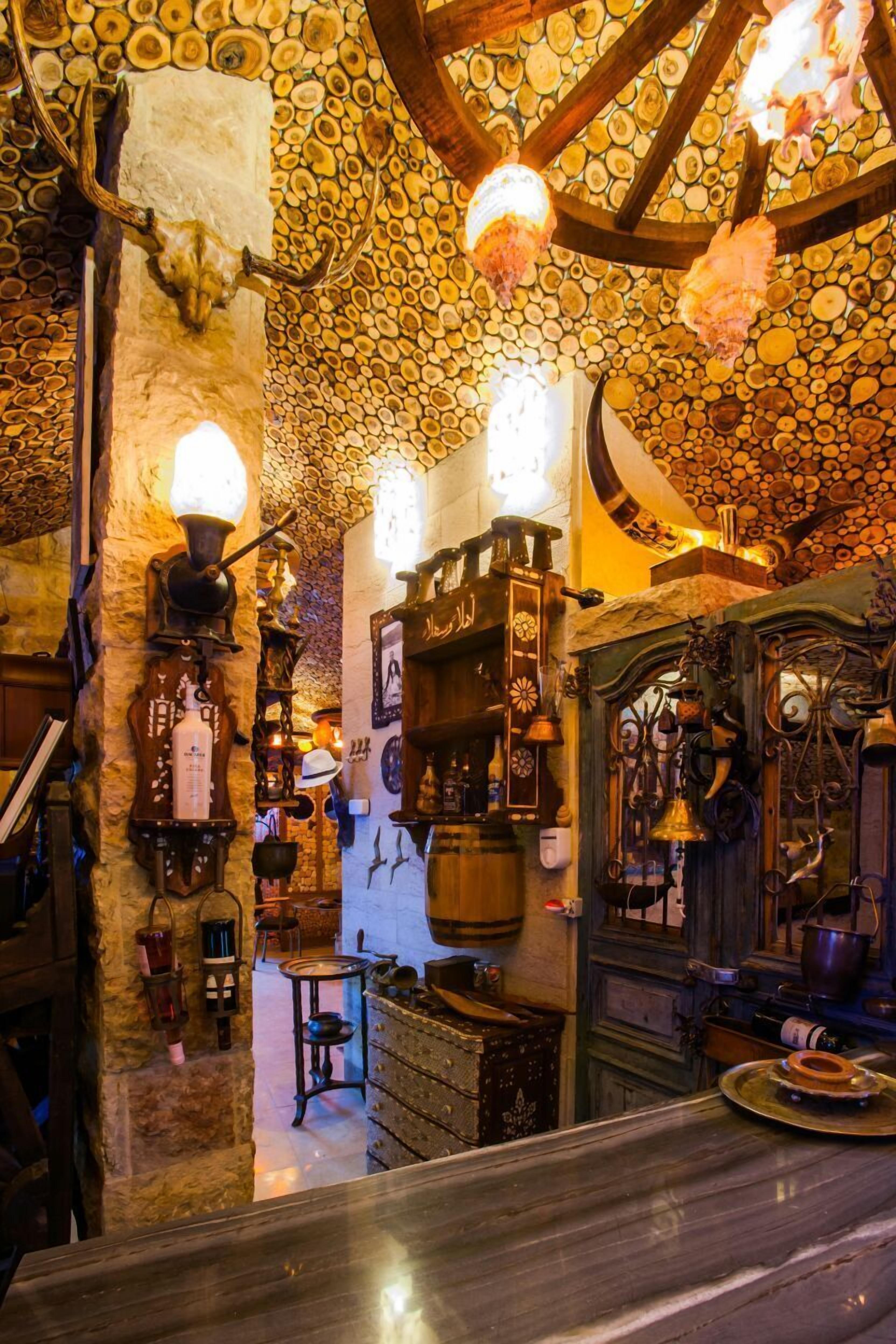 A rustic interior with a stone wall, wooden beams, and a variety of antique items displayed on shelves and walls.