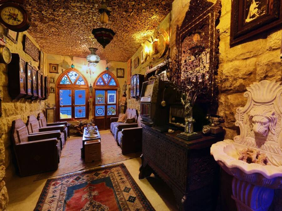 A cozy room with a stone wall, wooden furniture, and a large rug.