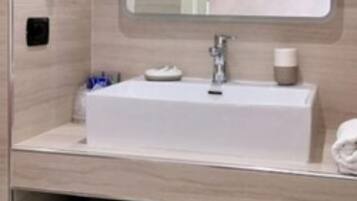 Un baño con lavamanos blanco, espejo, secador de pelo y toallero.