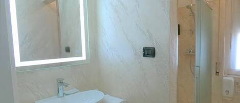A bathroom with a white sink, a mirror, and a glass shower enclosure.