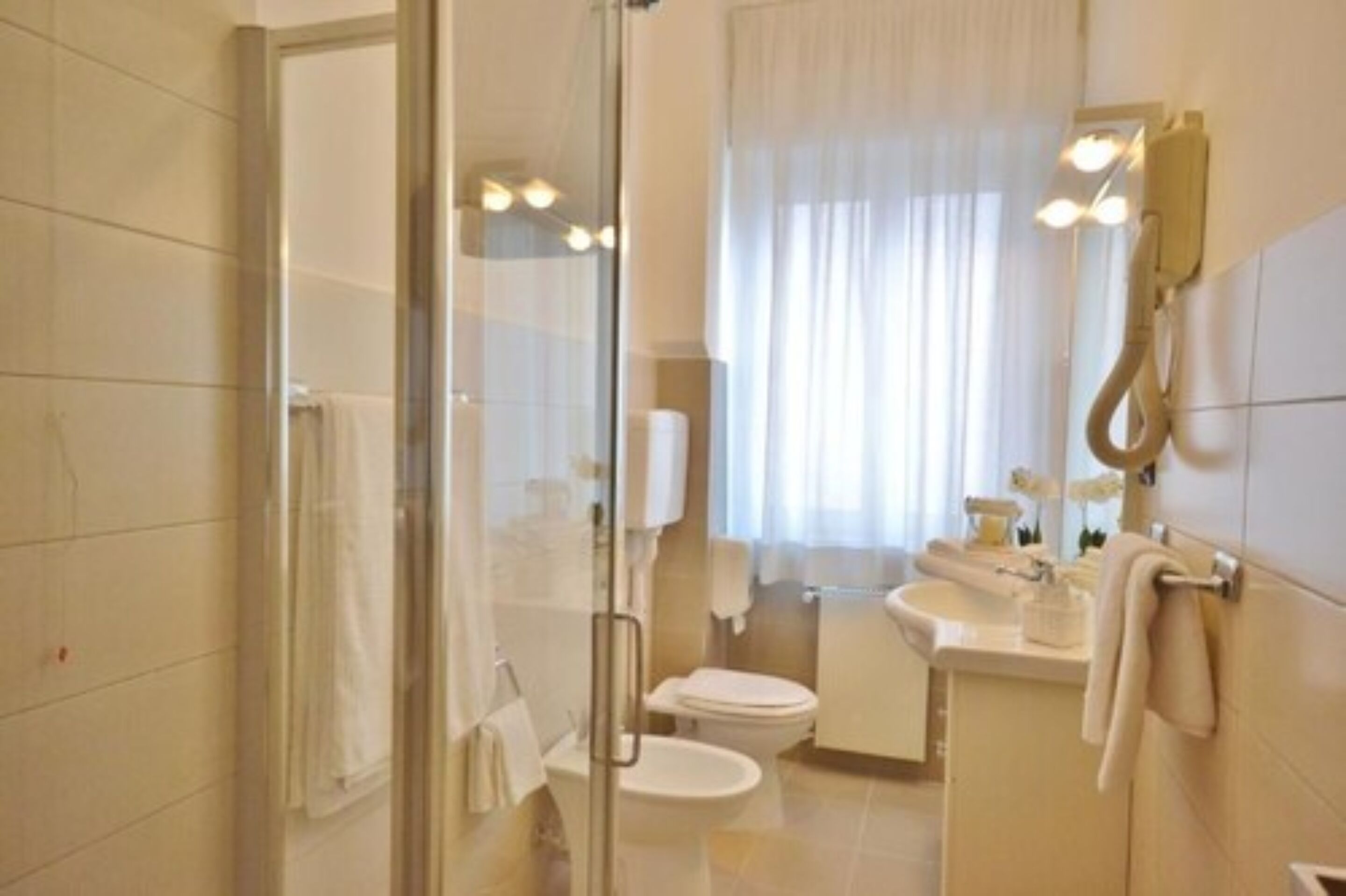 Un bany modern amb dutxa de vidre, un vàter i un lavabo amb mirall.
